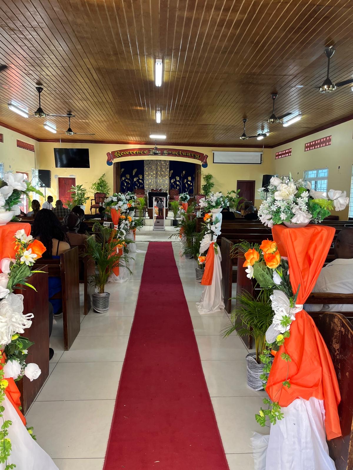 Church aisle decorated with orange and white flowers and drapery